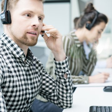 voip services phone.com man with headset talking using computer employees call center